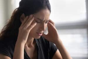 A close-up shot of a woman with her head in her hands because of stress