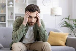 A man with opioid addiction and mental health challenges sitting with his head in his hands
