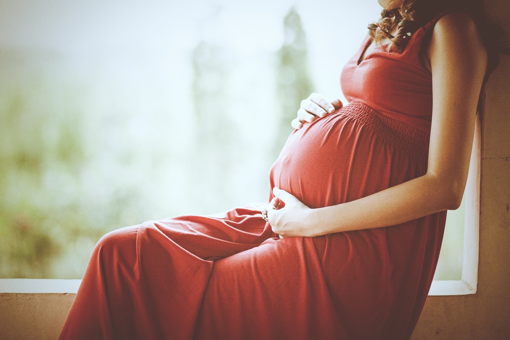 A cropped shot of a pregnant woman holding her stomach