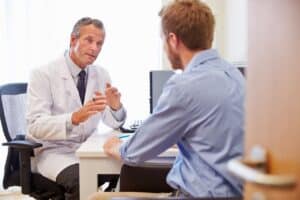 Doctor explains medication-assisted treatment to young man in his office