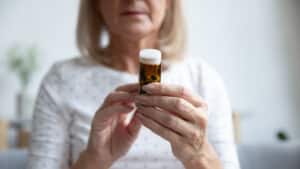 Woman holding a bottle of opioids, looking concerned, before starting methadone therapy