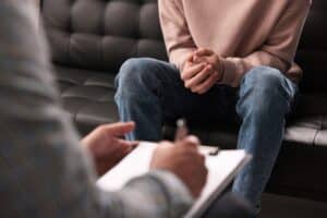 Man sits with folded hands, discussing his sobriety challenges with a counselor